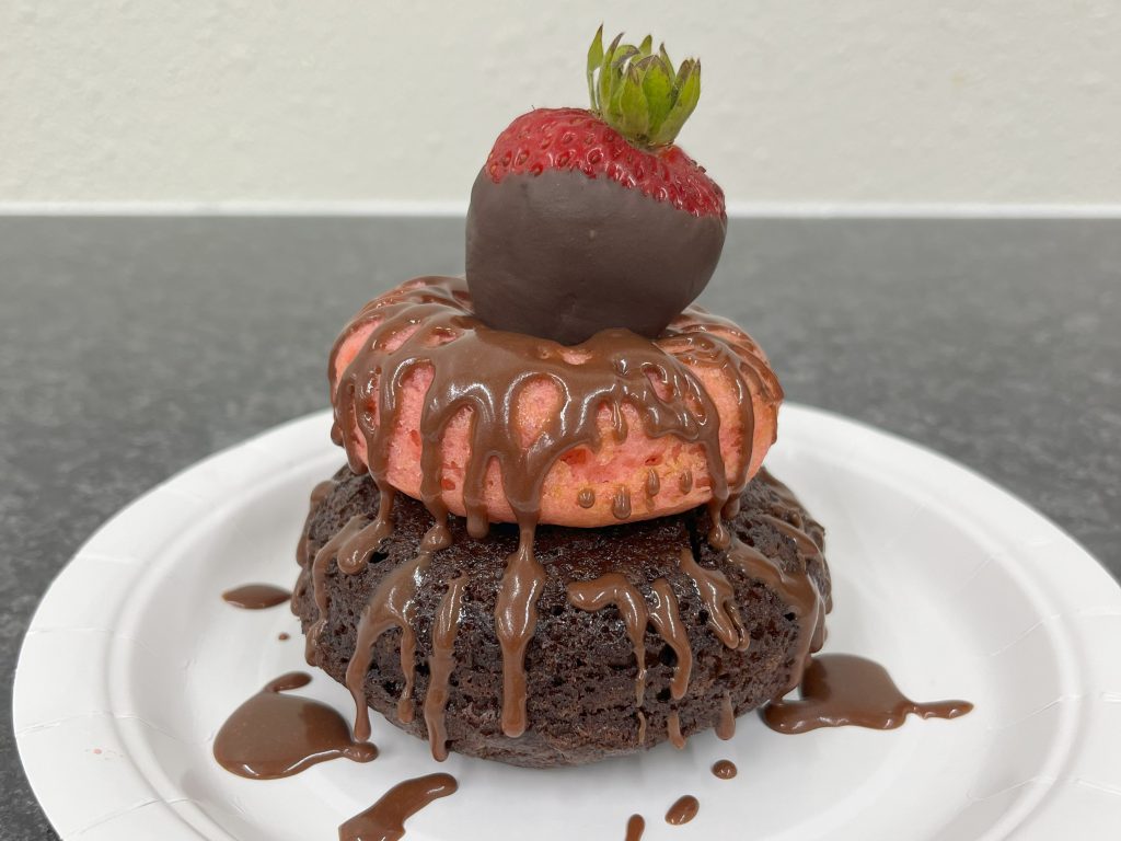 chocolate strawberry on top of a stack of one chocolate and one strawberry doughnut