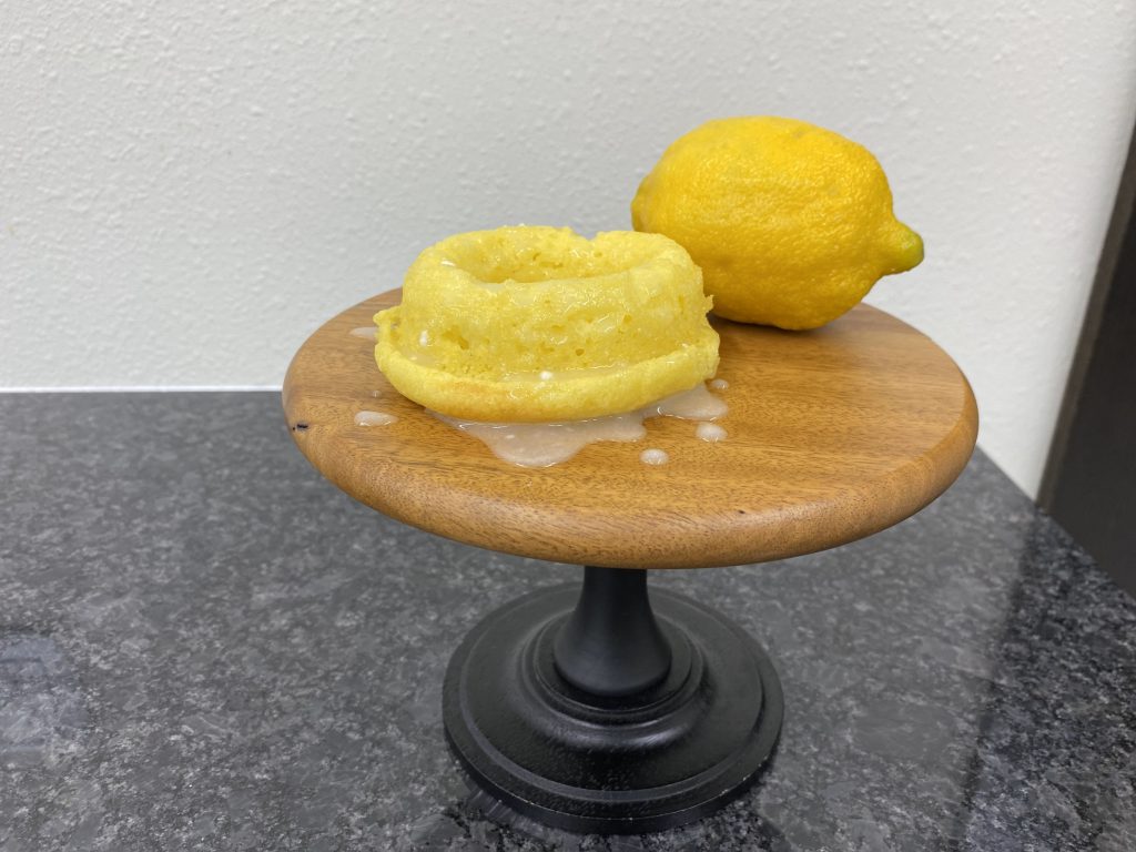 lemon doughnut with glaze and whole lemon on pedistal