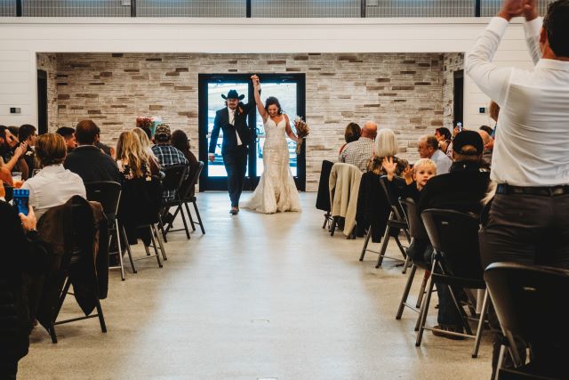 Mara wedding photo walking down the isle with hand raised