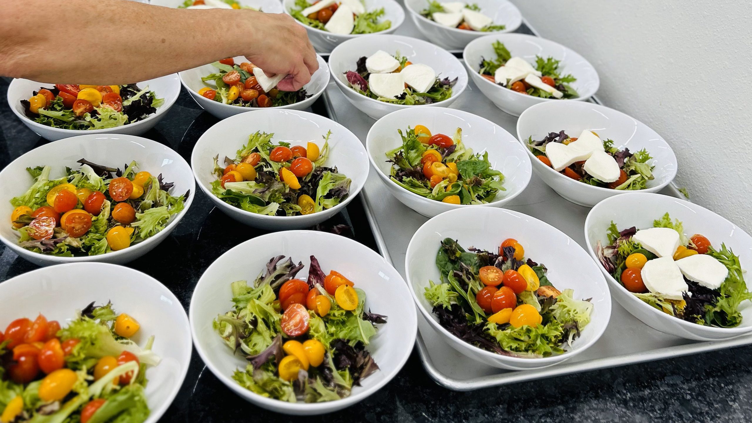 small bowls of salad lined up on the counter